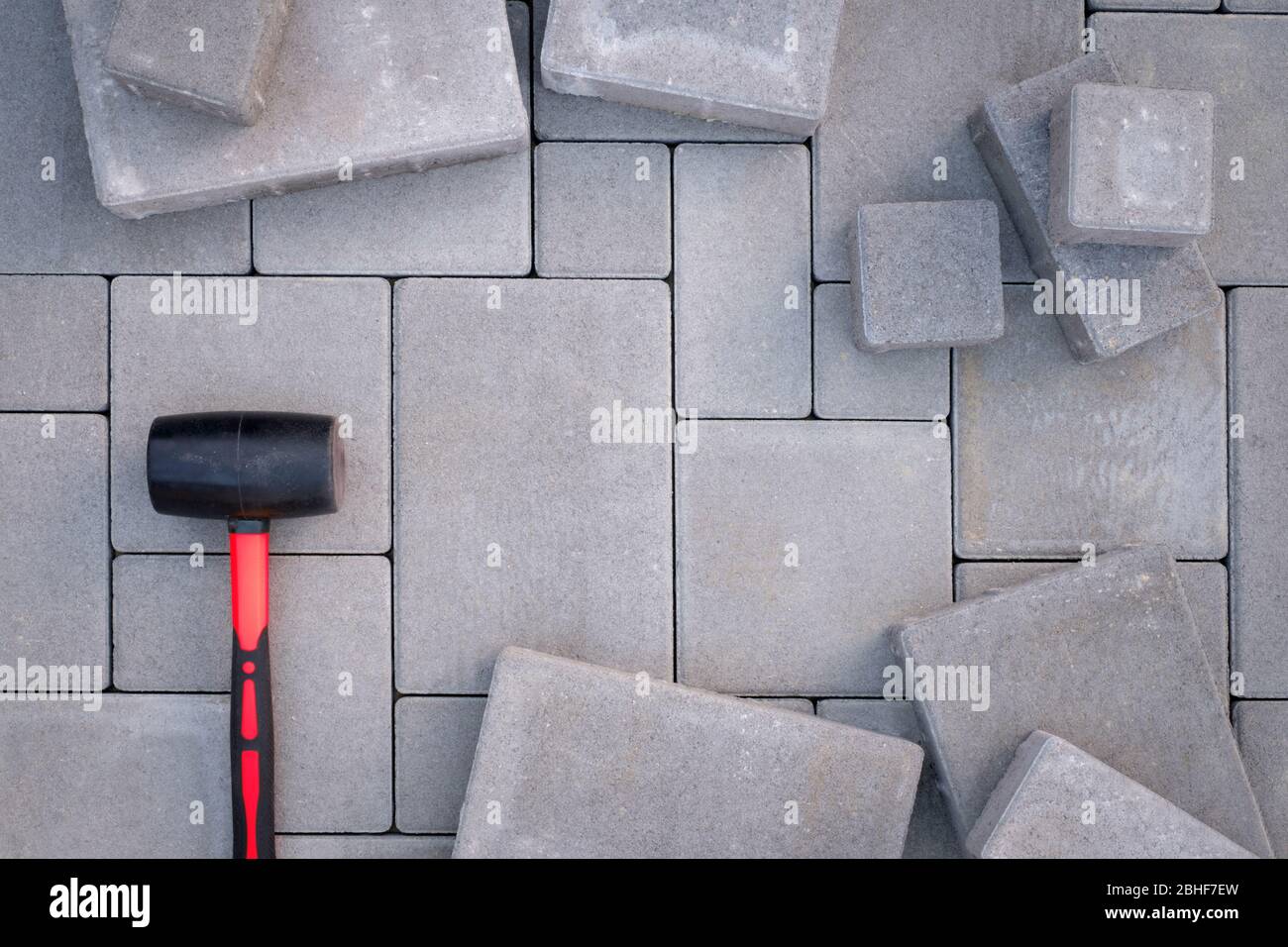 Paving stones paving background. Installing tools rubber hammer on foreground Stock Photo