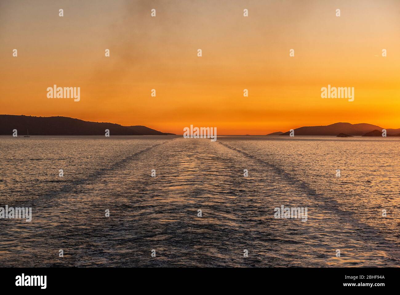 Adriatic Sea, Sea Croatia. The quiet of the sunset seen from the ship. The sun sets between the Croatian islands in the wake of the ship Stock Photo