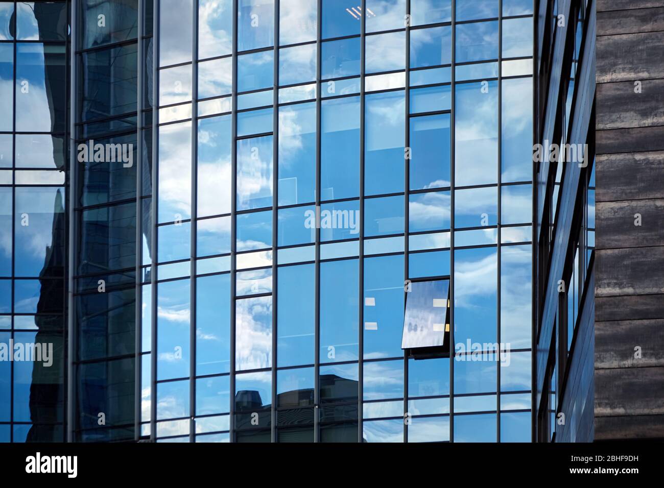 Windows of a skyscraper with reflection of blue sky and white clouds. A ...