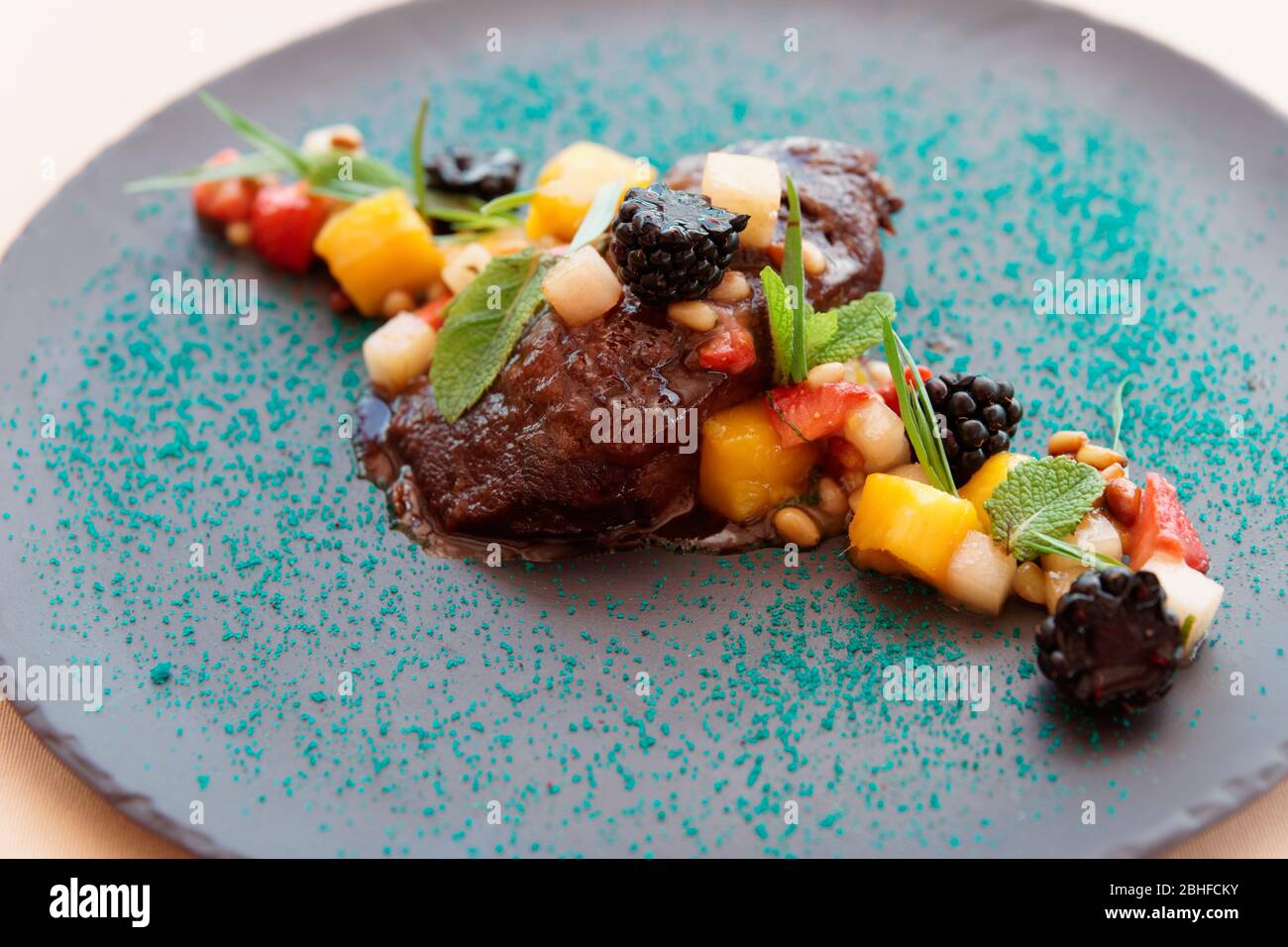 Braised veal cheek with fruits and berries on slate plate Stock Photo