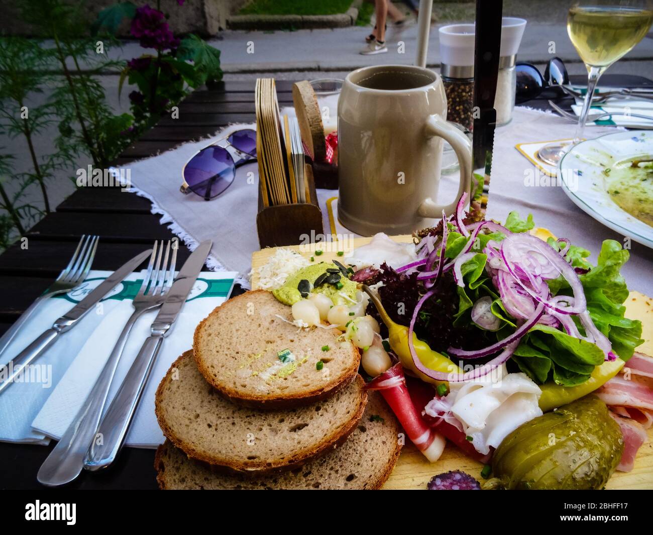 Austrian Brotzeit platter with wide selection of vegetables and sausages with beer. Daylight shot of typical bavarian dinner appetizer. Stock Photo