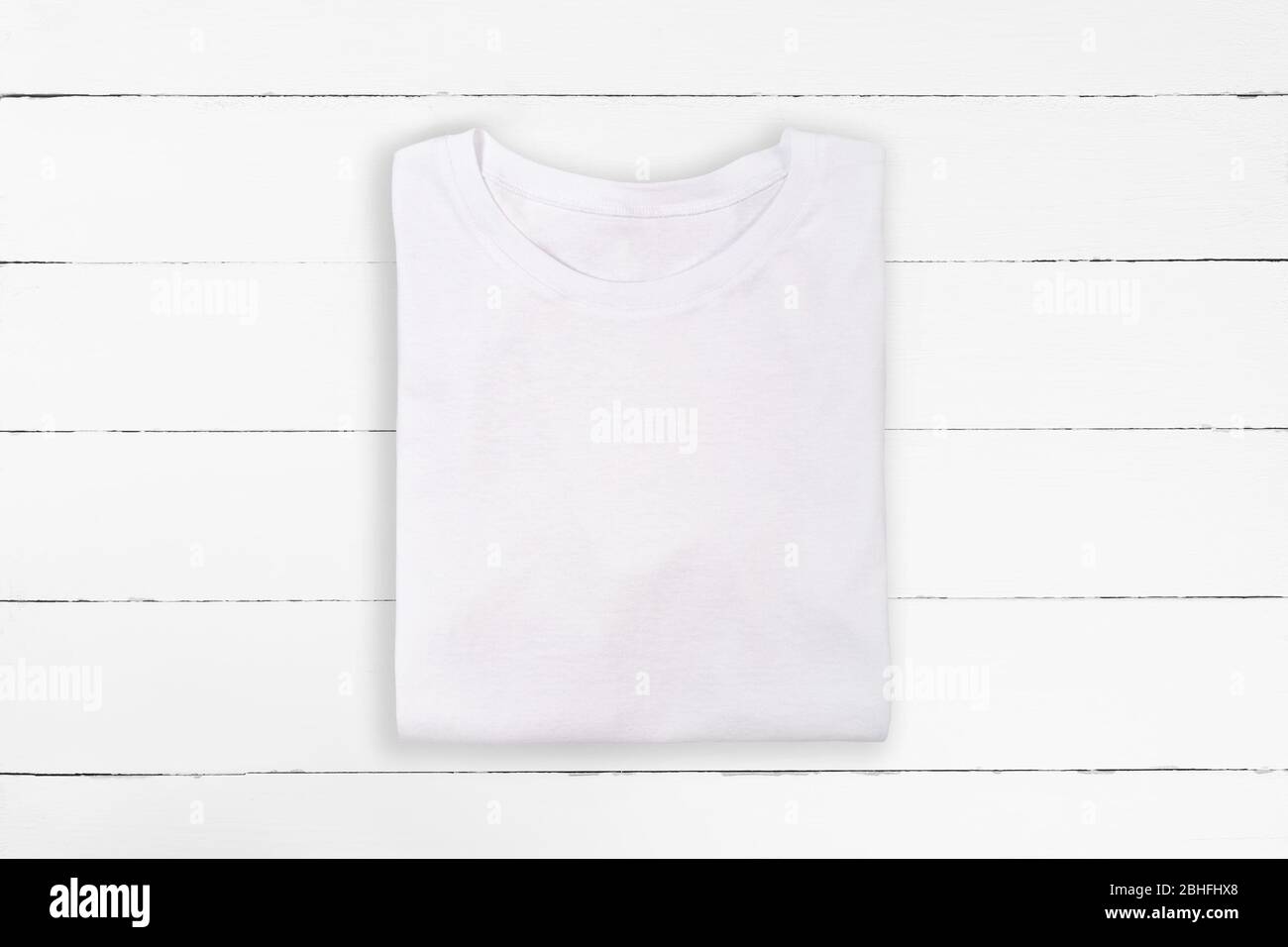 White folded blank t-shirt on white wooden background. White tshirt design template Stock Photo