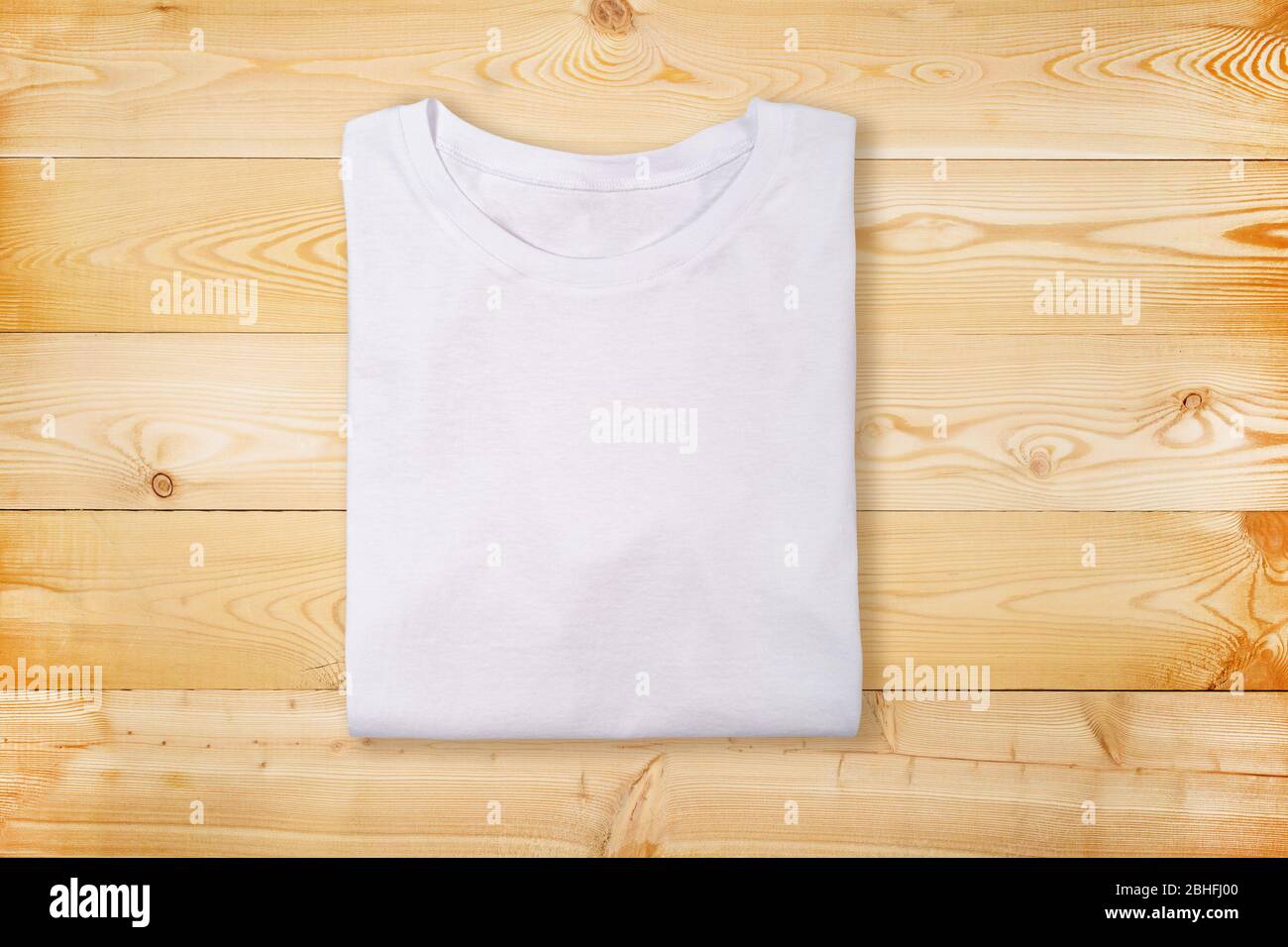 Blank white folded t-shirt on wooden background. Plain white tshirt on natural wooden texture Stock Photo