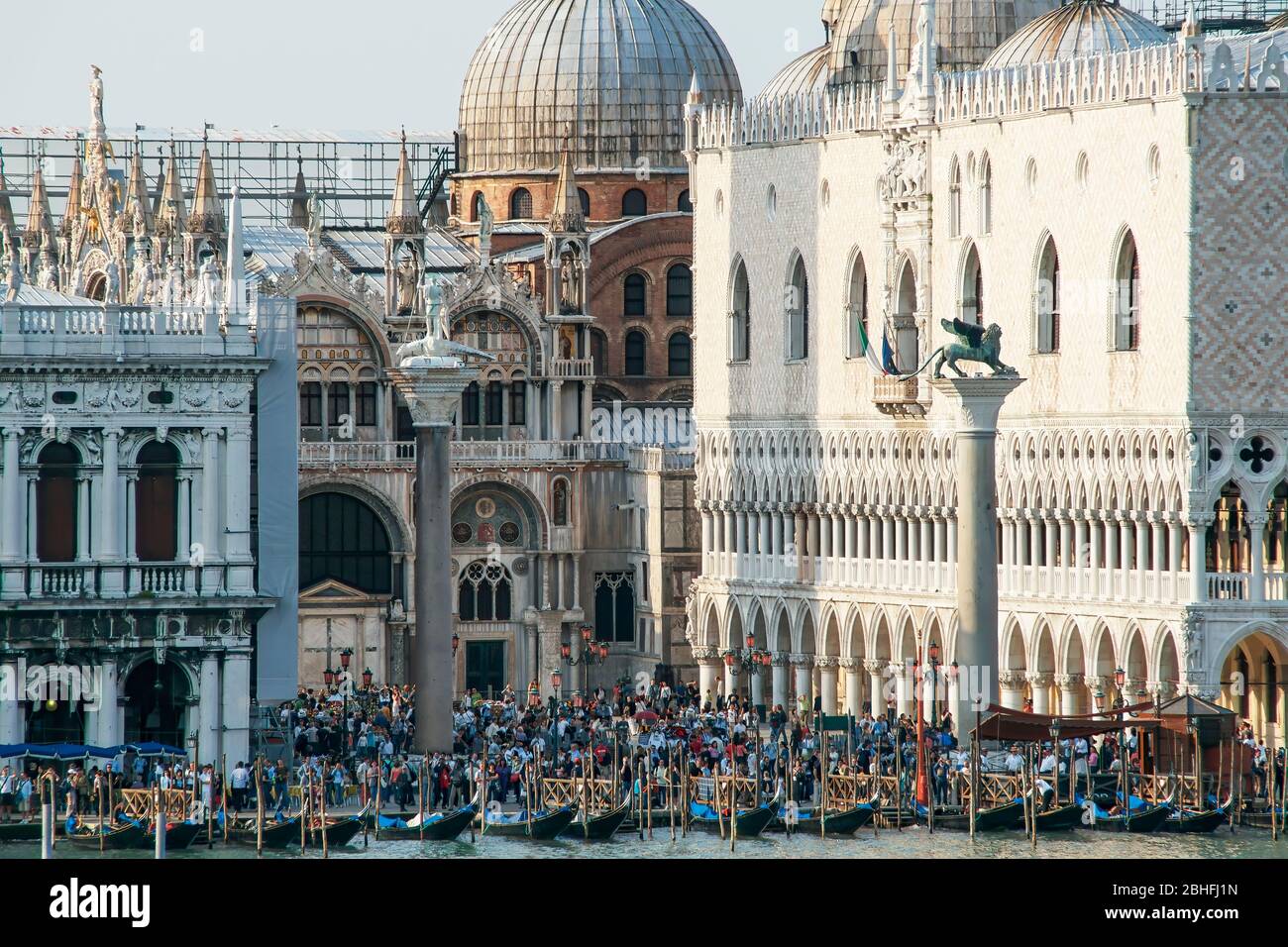 Crowds of people gather in Piazza San Marco. - Saint Mark's Square near the gondola docks on the Grand Canal. Venice, Italy. Late afternoon shadows. Stock Photo