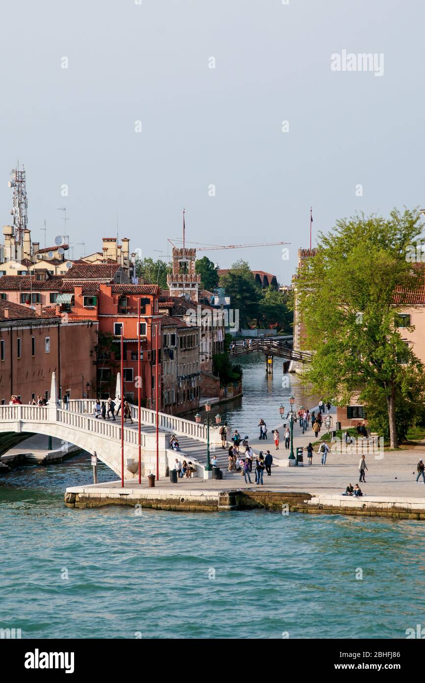 Everyday life. A bridge over the entrance to a small curving residential canal from the Grand Canal. People walking. Stock Photo