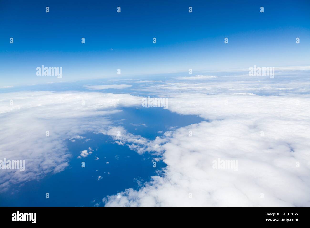 Aerial view from an aircraft window of flying above clouds and the Atlantic ocean Stock Photo