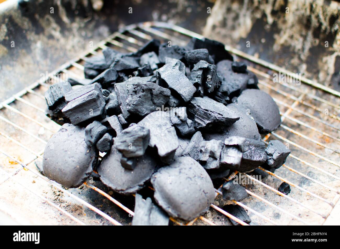 Charcoal briquettes filled in a small barbecue pit ready to be lit Stock Photo