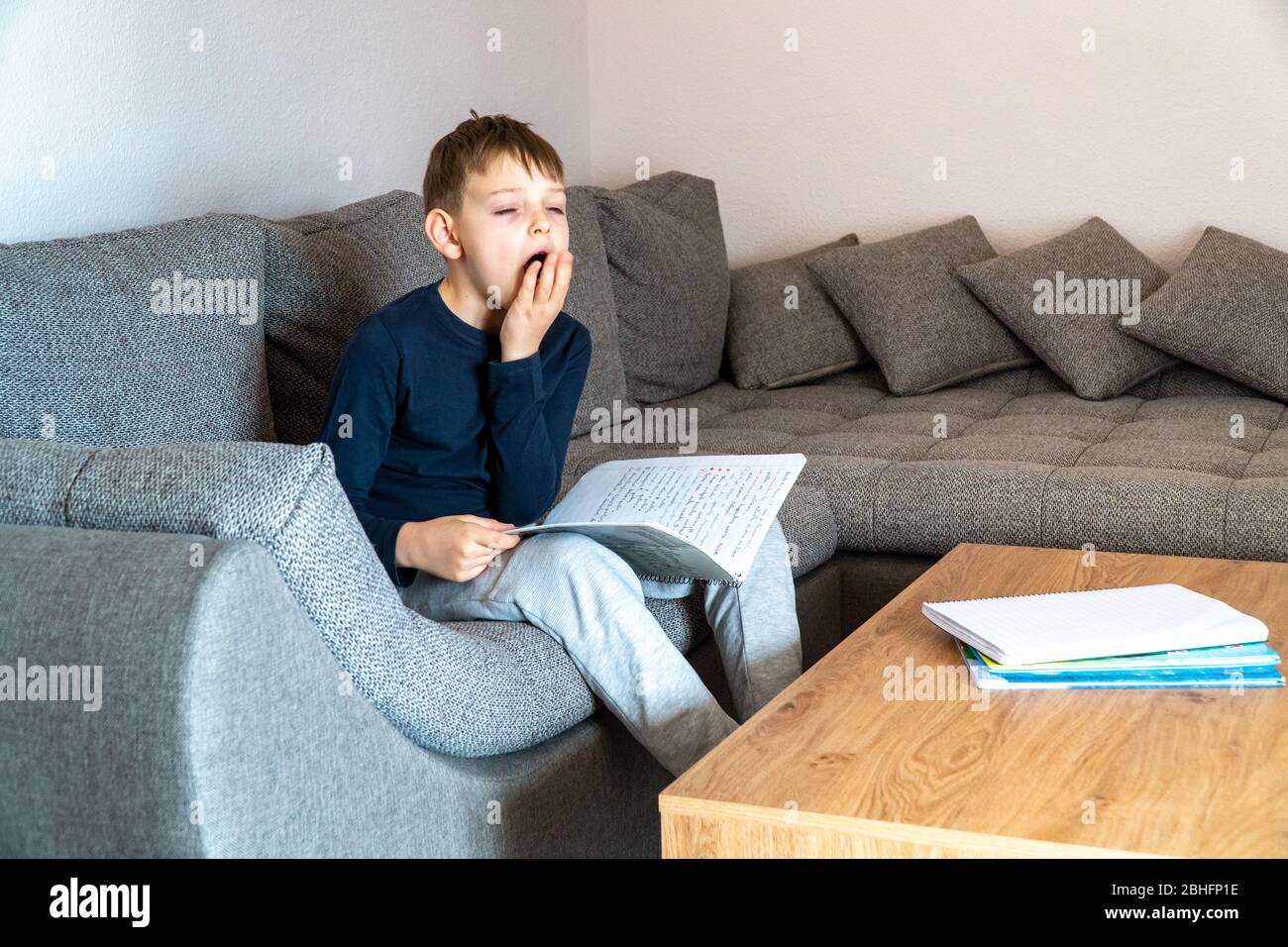 A yawning boy is bored studying at home. Self-study at home Stock Photo