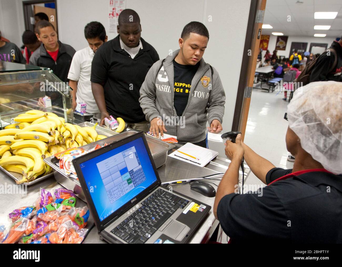 Cafeteria worker uses handheld scanner to read barcode information on