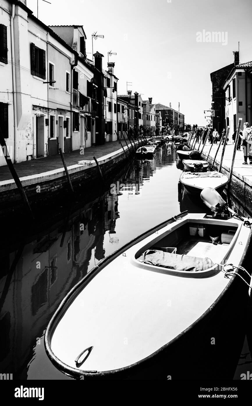 Boat moored in a narrow Venice canal surrounded by houses. Stock Photo