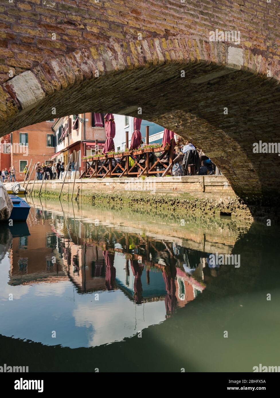 Venice, Italy - April 23, 2017: Characteristic brick pedestrian bridge that crosses one of the many navigable canals in Venice. Stock Photo