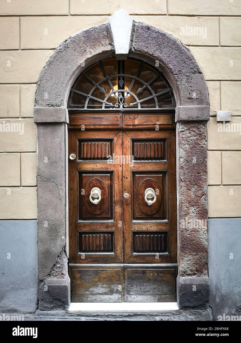 Ancient and solid wooden door with imposing stone arch. Stock Photo