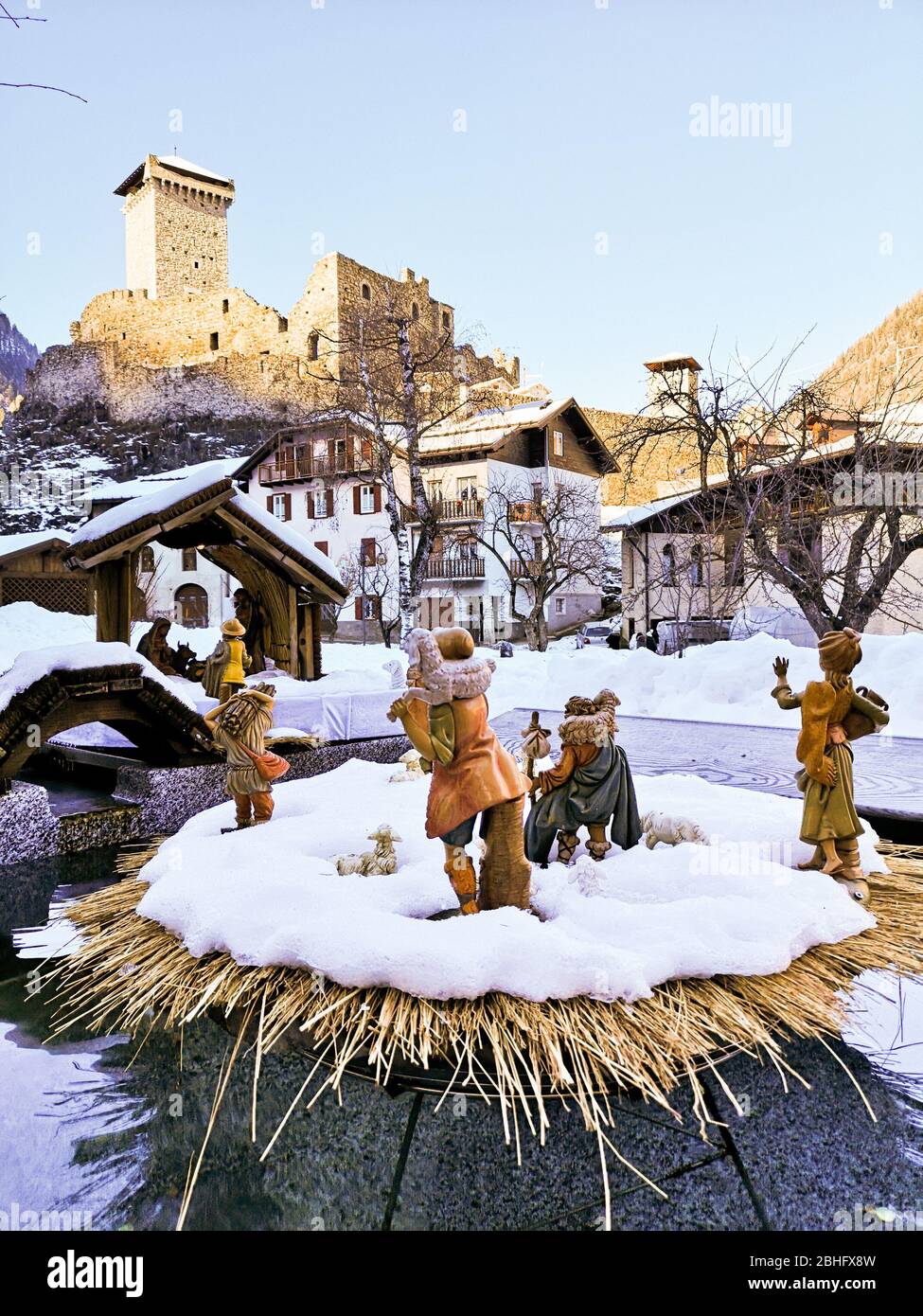 Ossana, Italy - December 26, 2019: Outdoor nativity scene covered in snow. In the background the famous castle of San Michele. Stock Photo