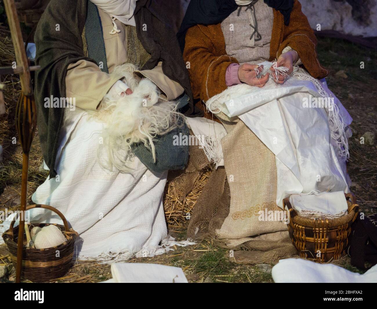 Women from a village work the wool and mend fabrics sitting on a straw bale. Stock Photo