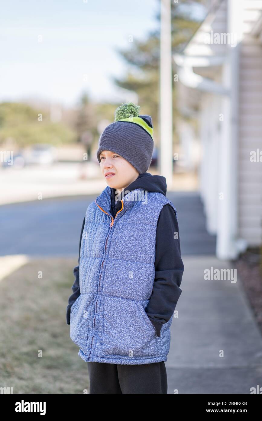 Portrait of a boy wearing vest and a hat, standing, looking away from the camera Stock Photo