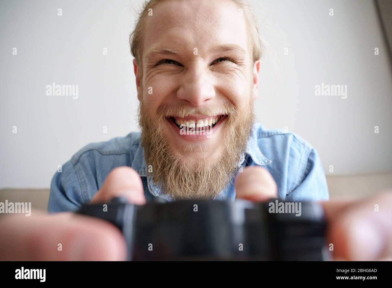 Funny happy young gamer holding joystick playing video game. Closeup. Stock Photo