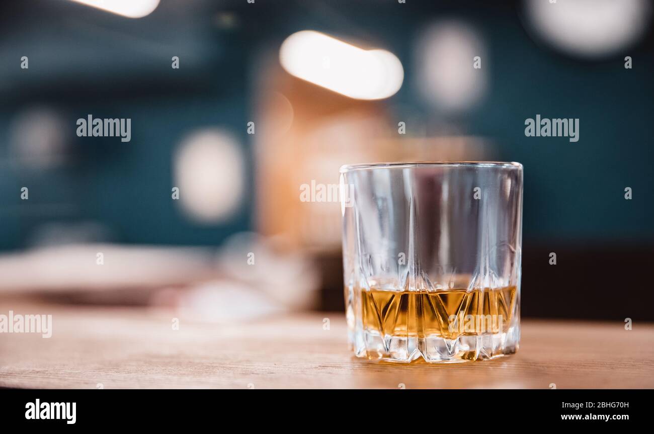 Glass with edges of yellow brown whiskey stands on bar counter in barbershop Stock Photo
