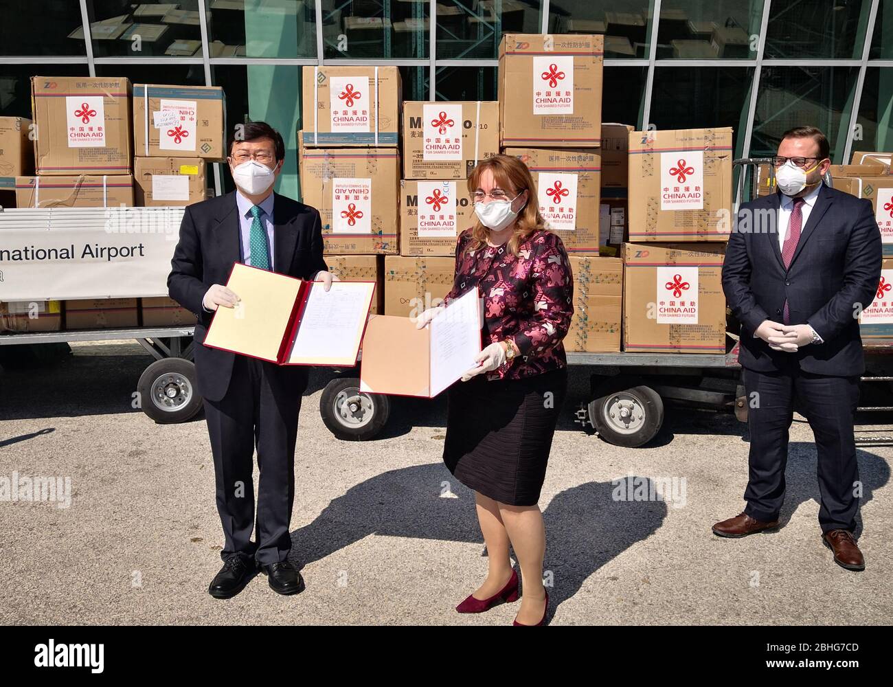 (200426) -- TIRANA, April 26, 2020 (Xinhua) -- Chinese Ambassador to Albania Zhou Ding (L) exchanges handover certificates with Albanian Deputy Minister of Health and Social Protection Mira Rakacolli (C) during a ceremony at Tirana International Airport, Albania, April 25, 2020. A batch of medical supplies donated by the Chinese government arrived at Albania's Tirana International Airport on Saturday to help the country fight the coronavirus pandemic. The medical supplies include testing kits, protective garments, face masks, goggles and gloves. (Chinese Embassy to Albania/Handout via Xinh Stock Photo