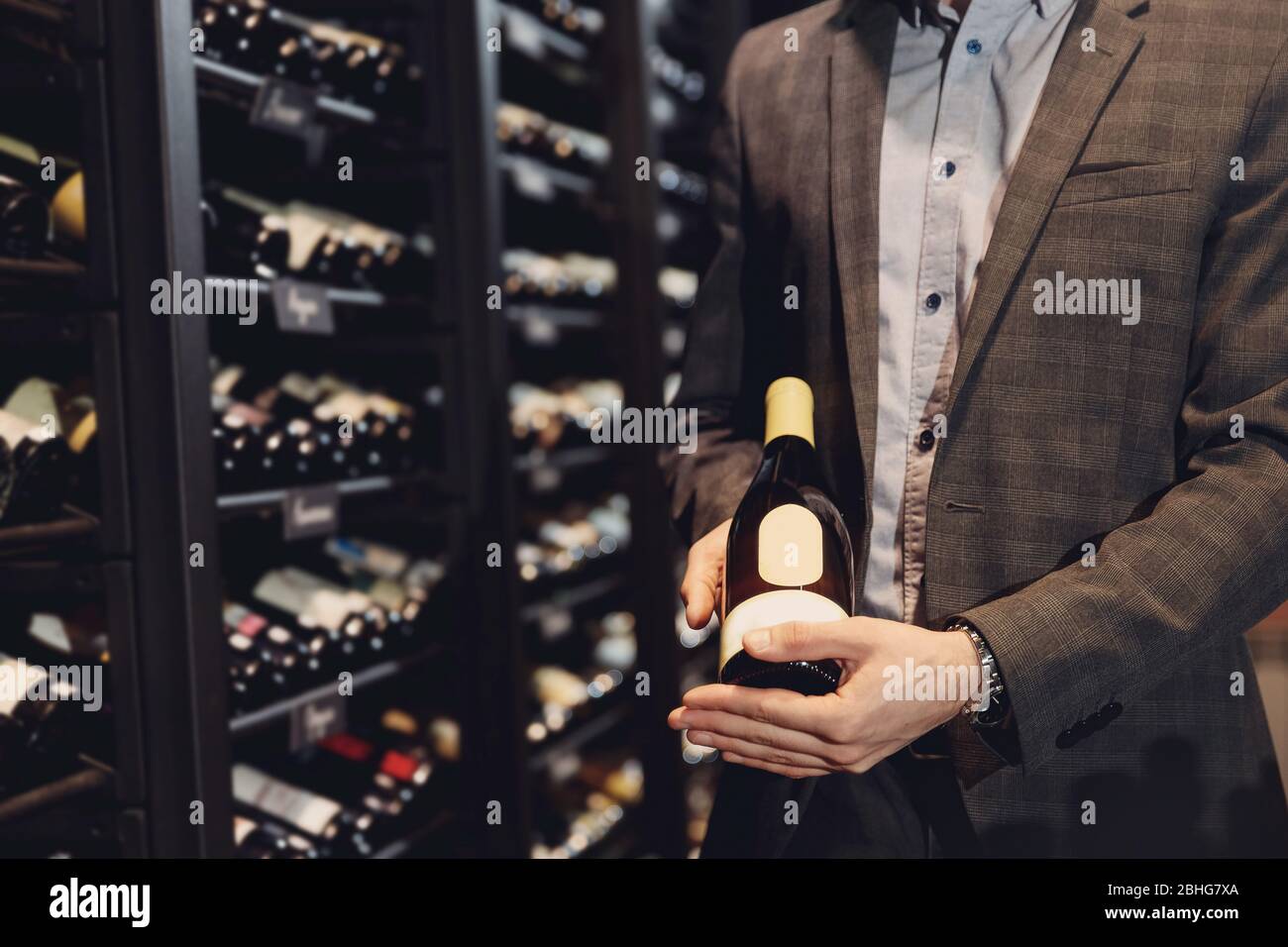 Bartender sommelier picks bottle of wine from rack in restaurant with exquisite drinks Stock Photo
