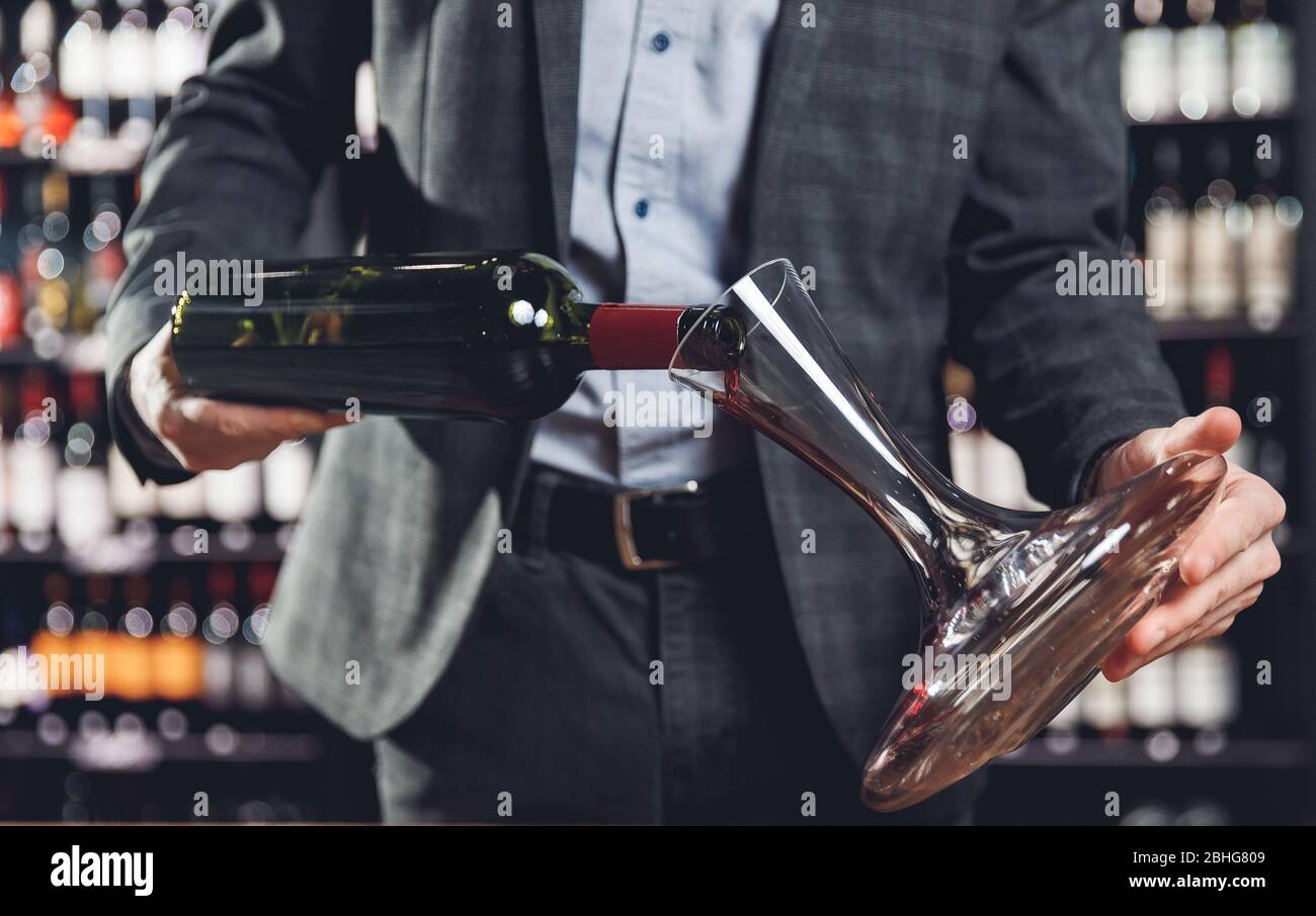 Sommelier pouring red wine into carafe decanter to make aeration drink