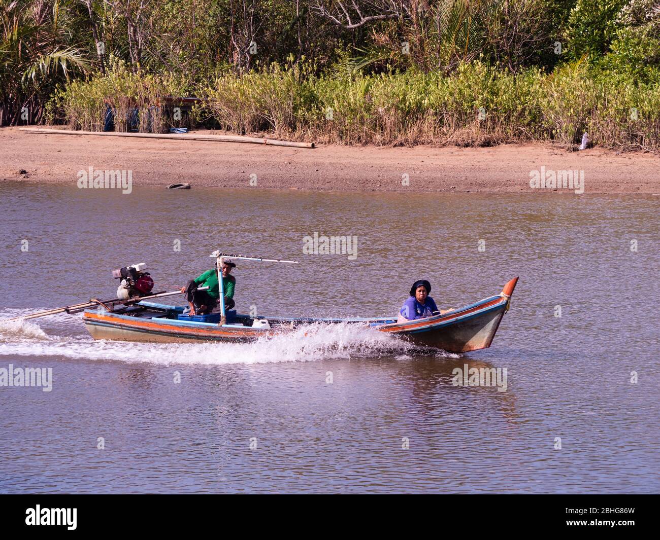 Small long tail vessel with man and woman on board at Mak Bang, Satun City, Satun in the south of Thailand. Stock Photo