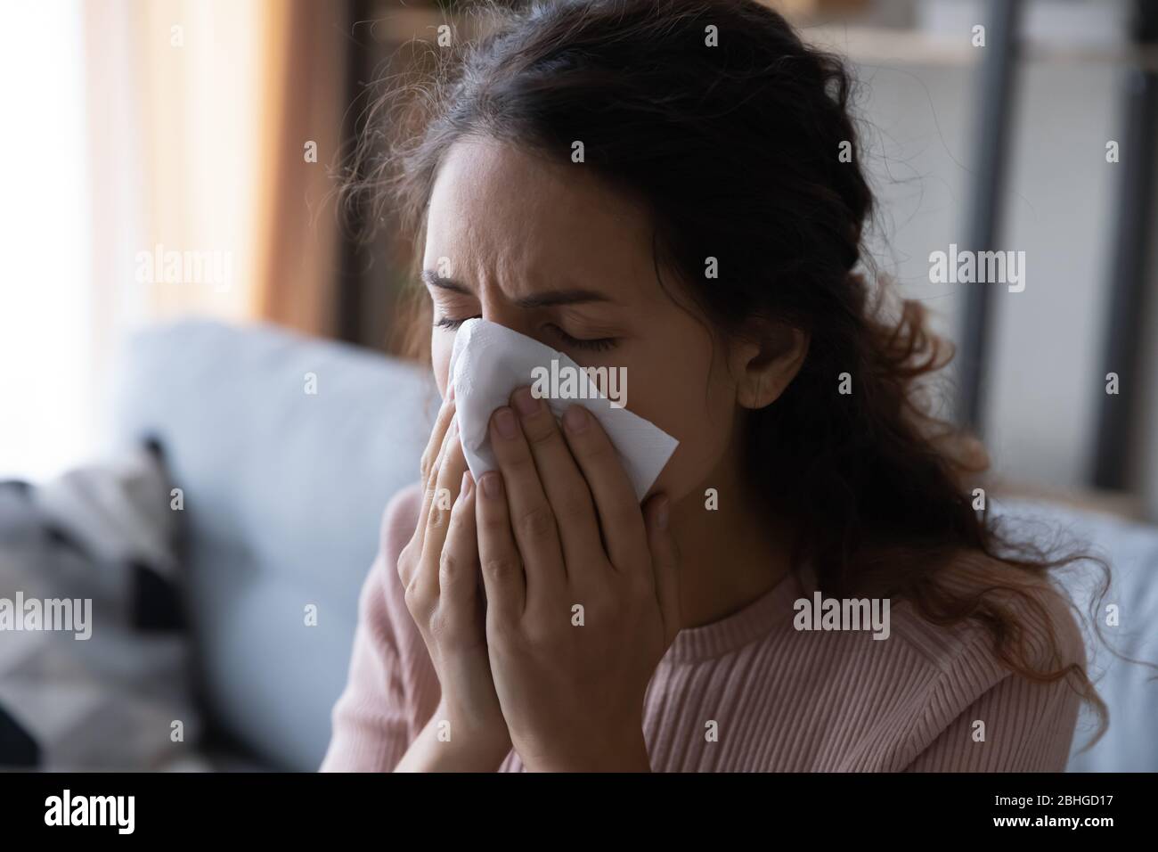 Unhealthy young lady using paper tissue, wiping runny nose Stock Photo