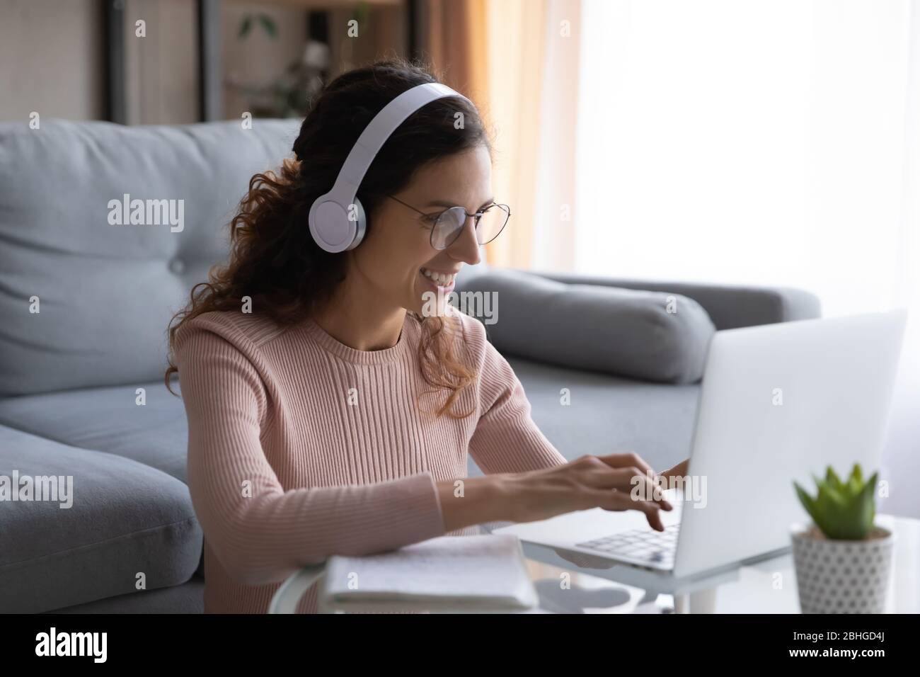 Happy millennial woman student in glasses studying on online courses. Stock Photo
