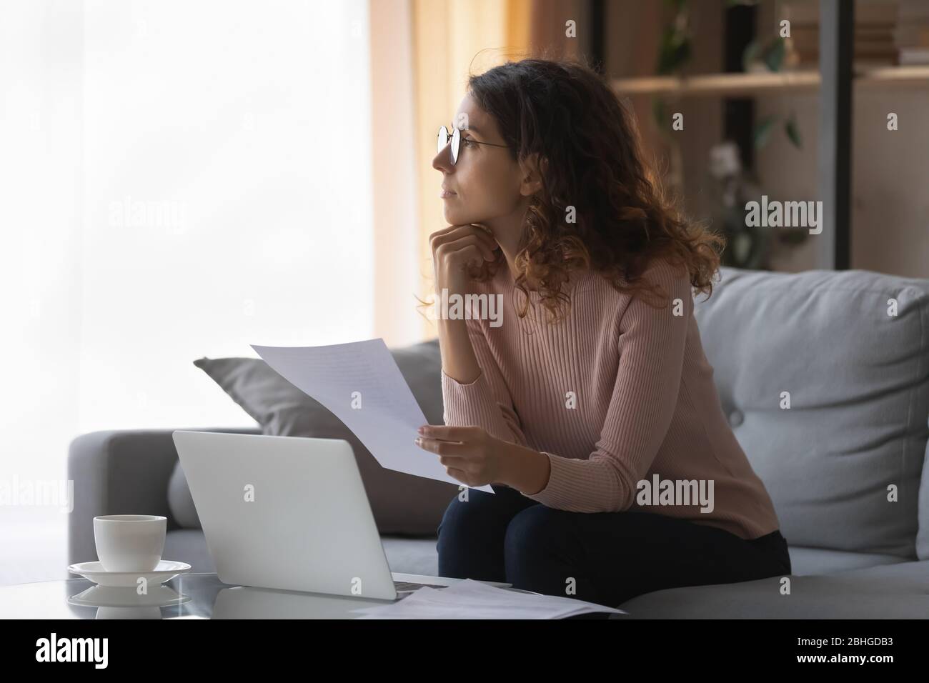 Distracted from work or study young pretty woman looking away. Stock Photo