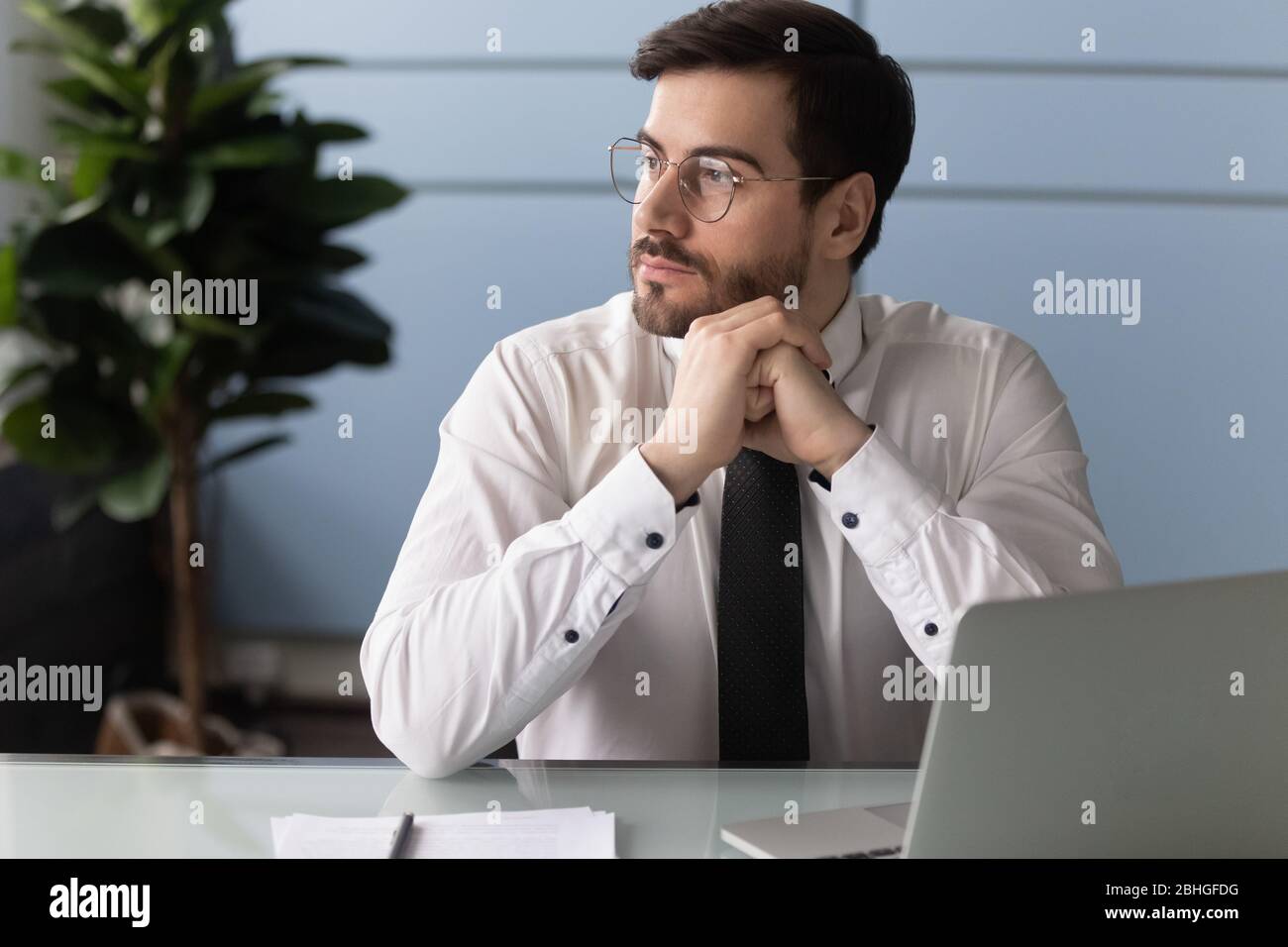Thoughtful businessman using laptop, pondering online project. Stock Photo