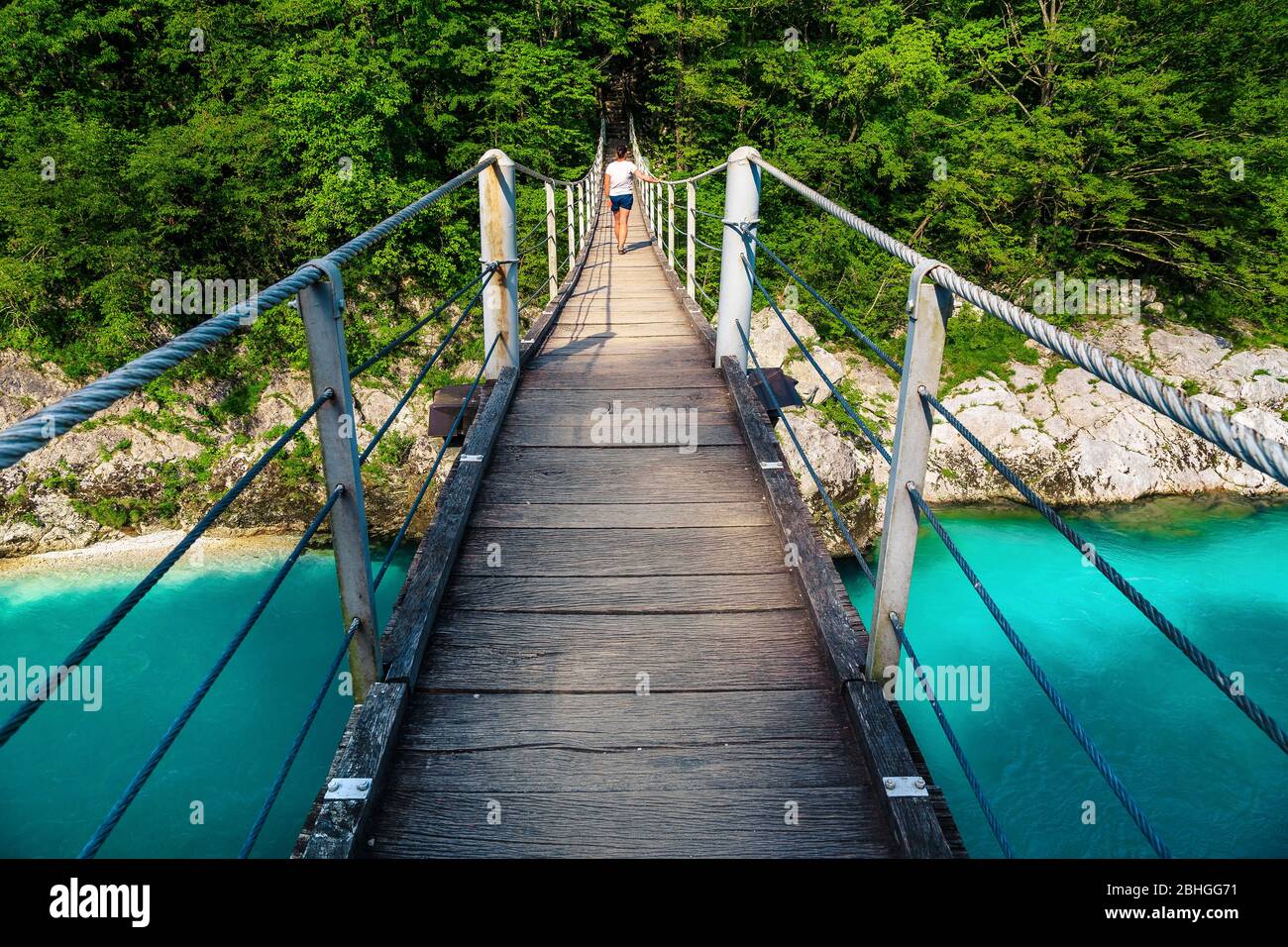Stunning hiking trail with hiker on the suspended bridge over the Isonzo river in the forest, Kobarid, Slovenia, Europe Stock Photo