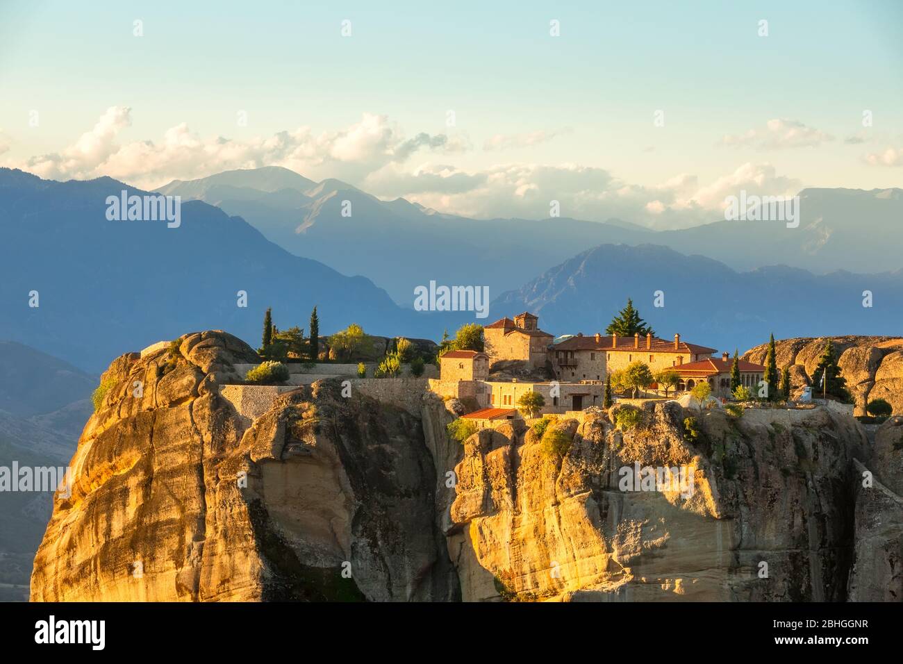 Greece. Summer sunset in Meteora. Rock monastery on a background of clouds over the mountain peaks Stock Photo