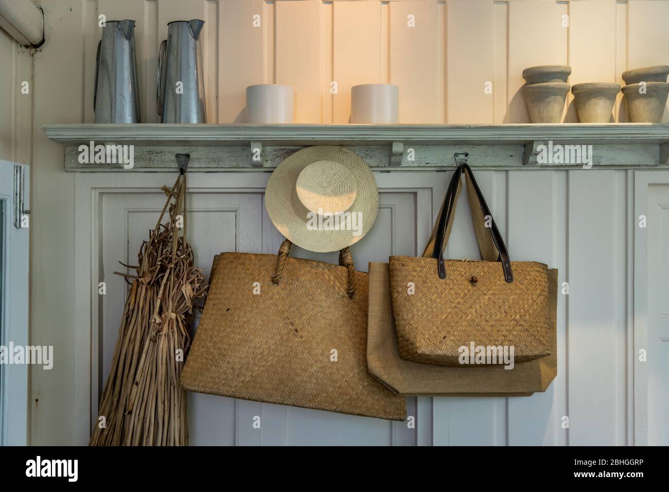 Accessories for women, Beautiful straw hats in retro style and vintage  woven handbags hang on wooden house wall. trendy Stock Photo - Alamy