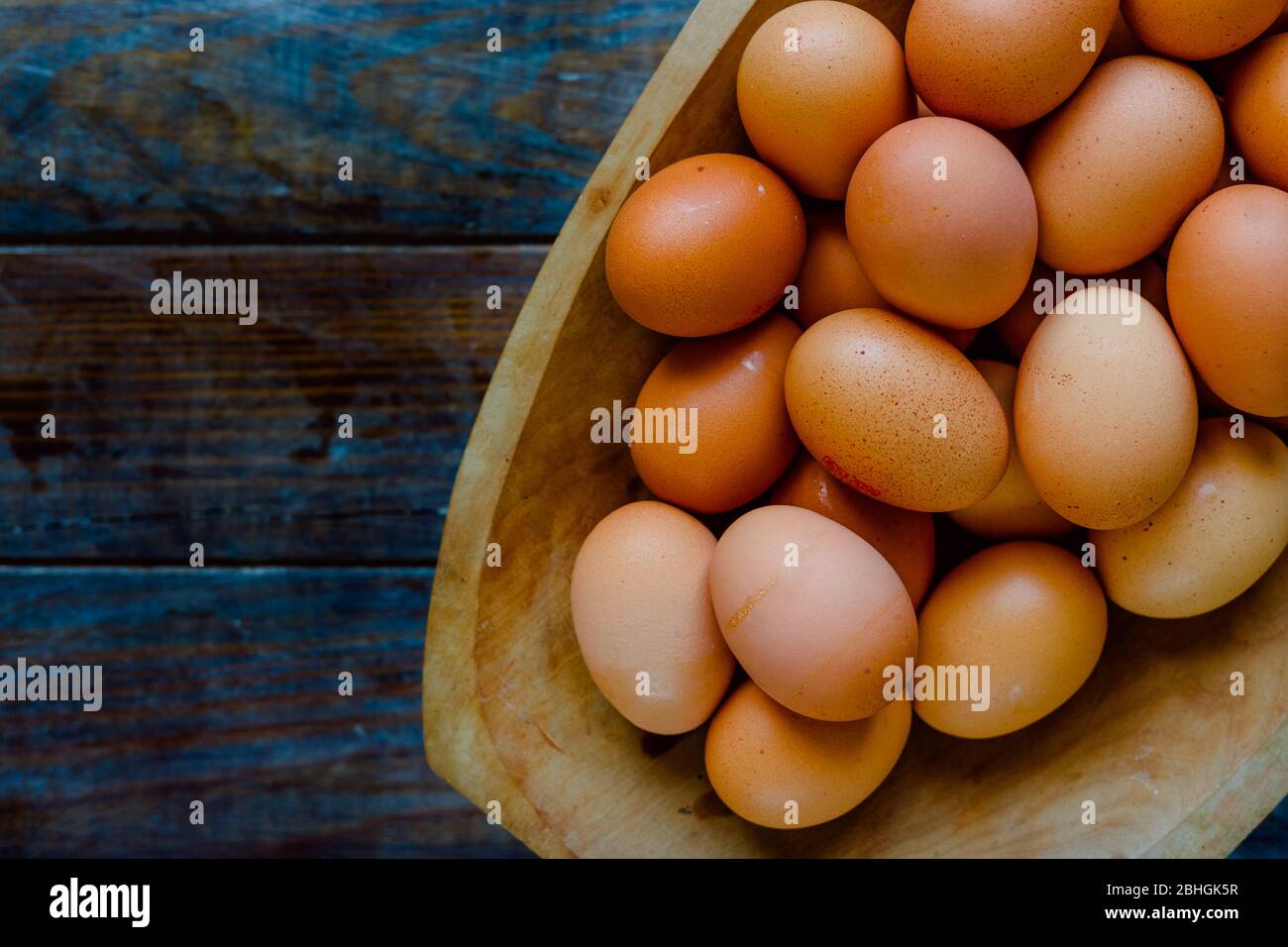 Organic eggs in a large wooden bowl on a wooden table Stock Photo