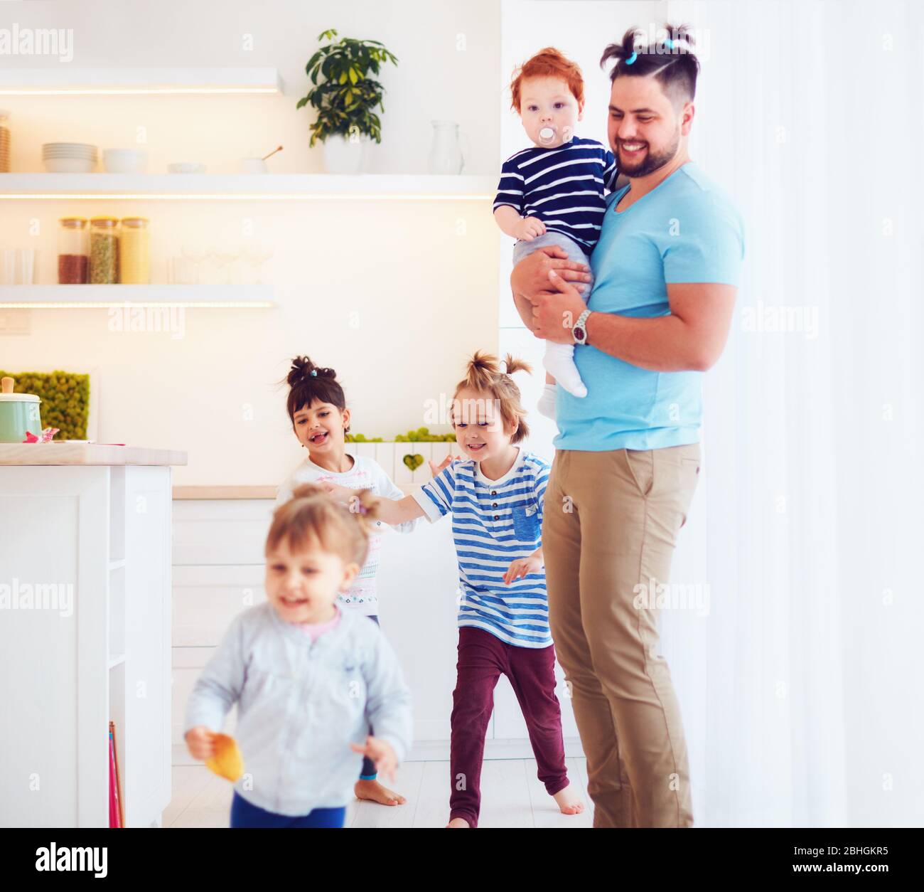 father with weird hairstyle looking after mad kids at home Stock Photo