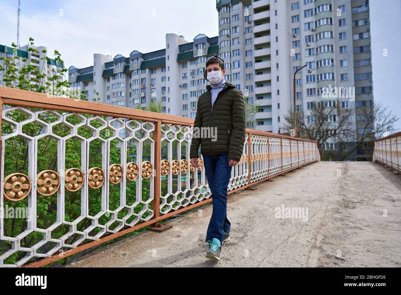 View of teen boy walks down the street during the day, a pedestrian walkway and ...