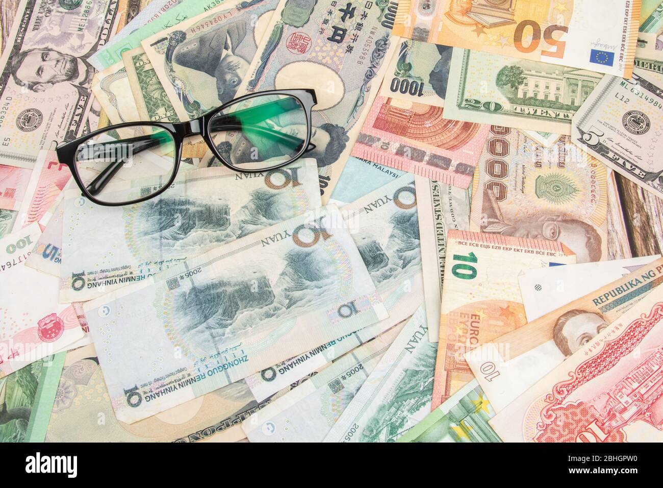 Vædde Tilskyndelse Idol Eye glasses with World international banknotes vary countries background.  US Dollar, Chinese yuan, Japanese yen, Euro, Korea won, Thai baht. Concept  o Stock Photo - Alamy