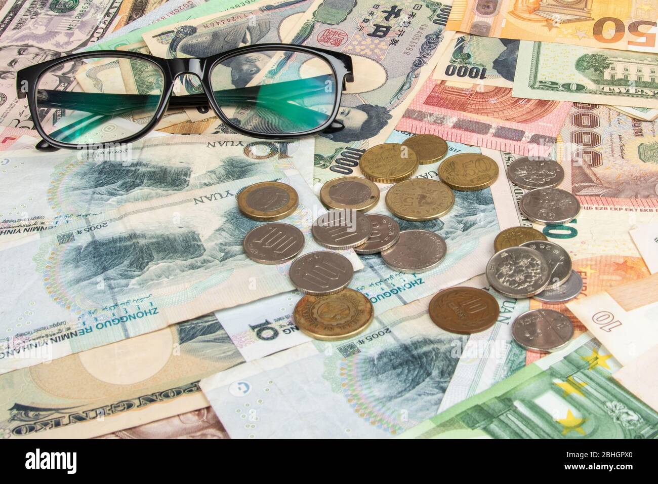 Eye glasses with World international banknotes vary countries background. US Dollar, Chinese yuan, Japanese yen, Euro, Korea won, Thai baht. Concept o Stock Photo