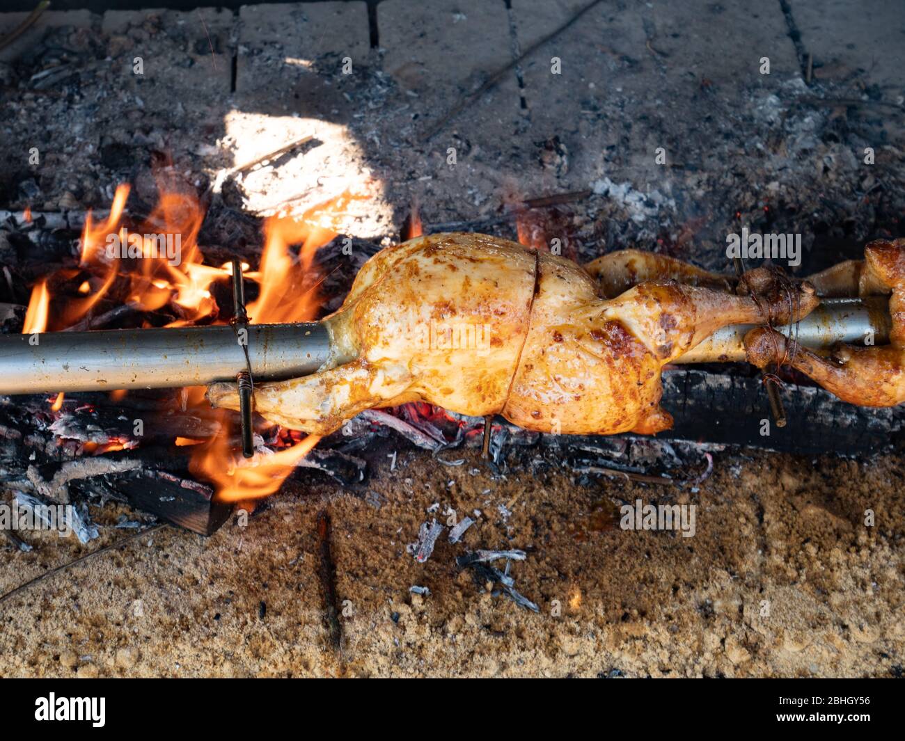 Man chef spray spicy marinate on roast Chicken on the BBQ steel bar in