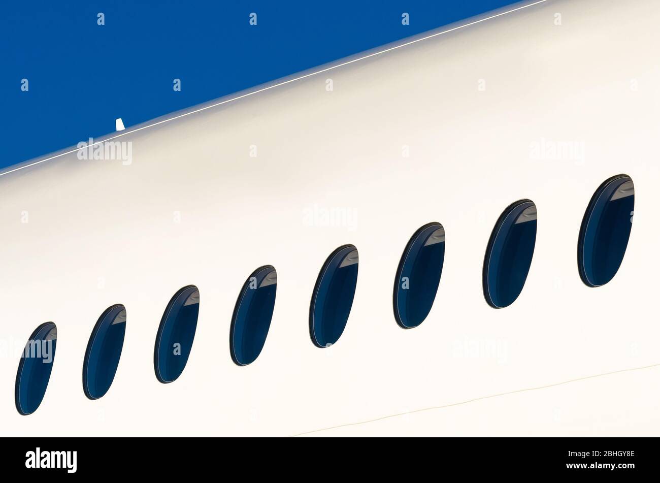 Portholes on white modern airplane and sky. Stock Photo