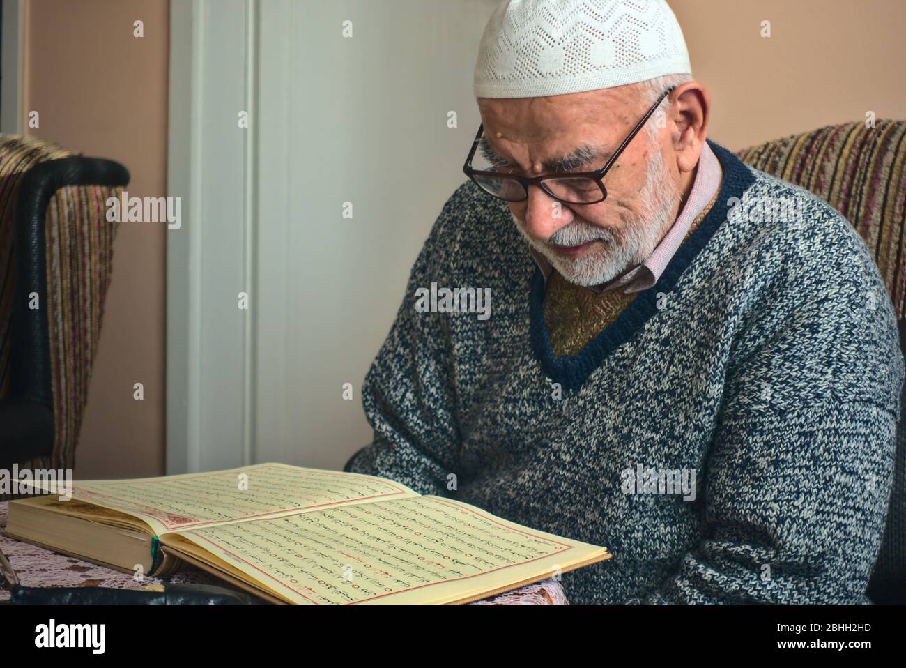 Elderly Turkish muslim male reciting the holy book of Islam, Qur'an in Ramadan month before iftar Stock Photo