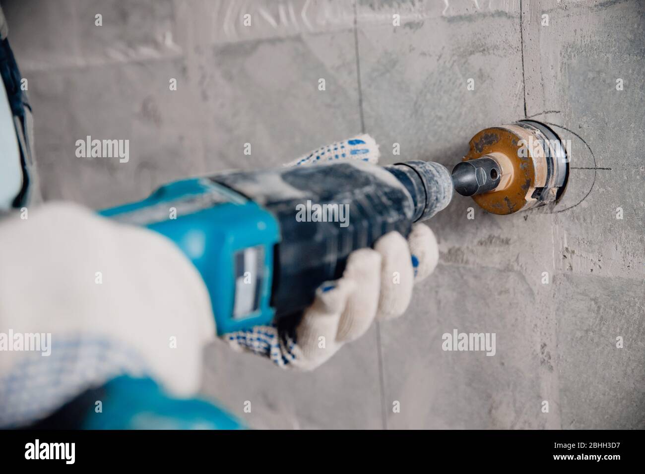 Builder worker pneumatic hammer drills hole in concrete brick wall with