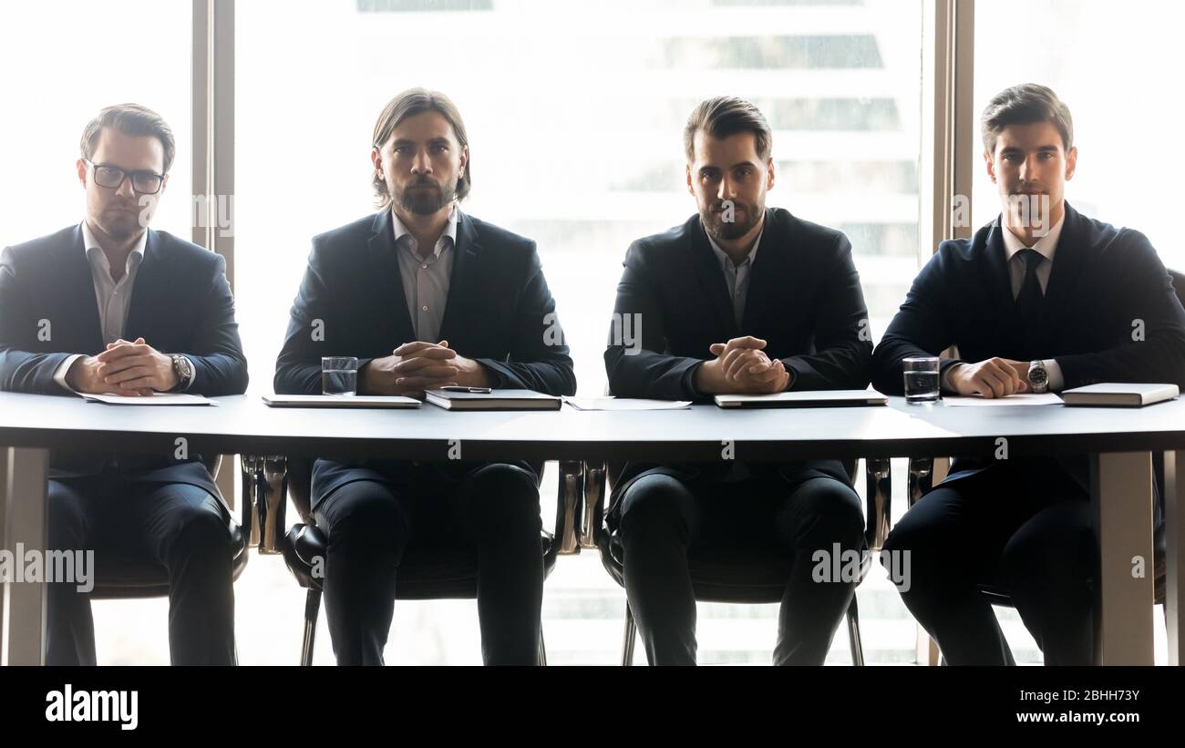 Four serious businessmen sitting in row at meeting Stock Photo