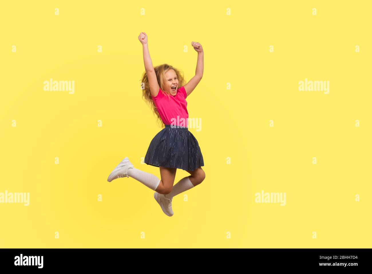 I am champion! Full length portrait of ambitious little girl in dress jumping in air and shouting from happiness, inspired child celebrating success. Stock Photo