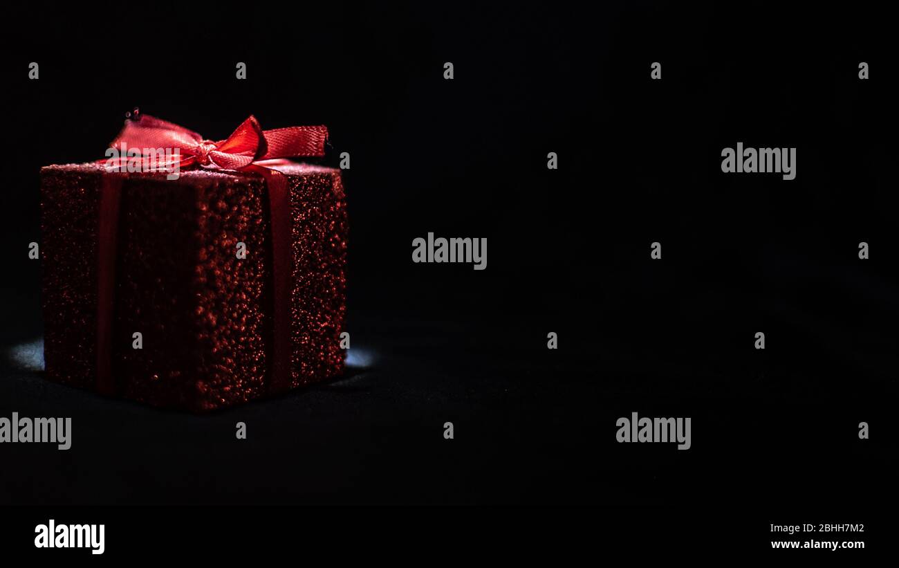 red gift box on black background Stock Photo - Alamy