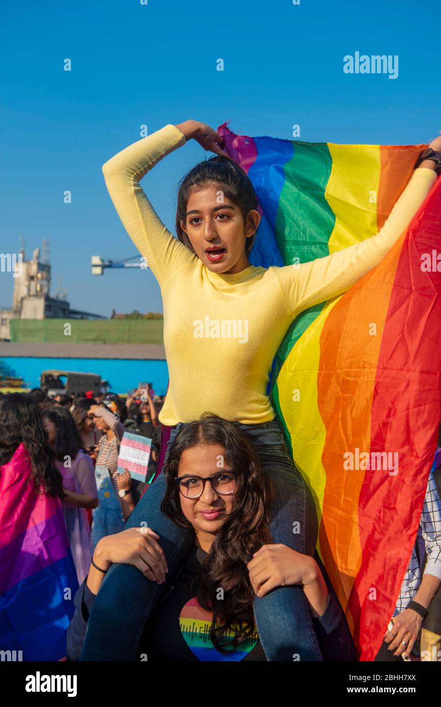 Mumbai / India 01 February 2020  Indian LGBT community girl sitting on shoulders of another girl and      waving rainbow color flag during pride parad Stock Photo