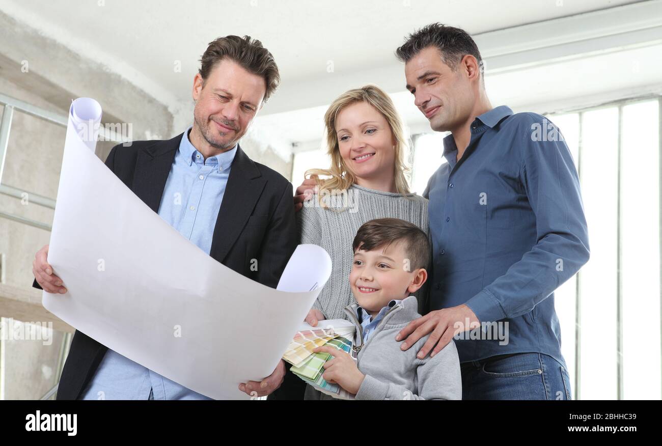 Architect showing house design plans to a family with child. Meeting at ...