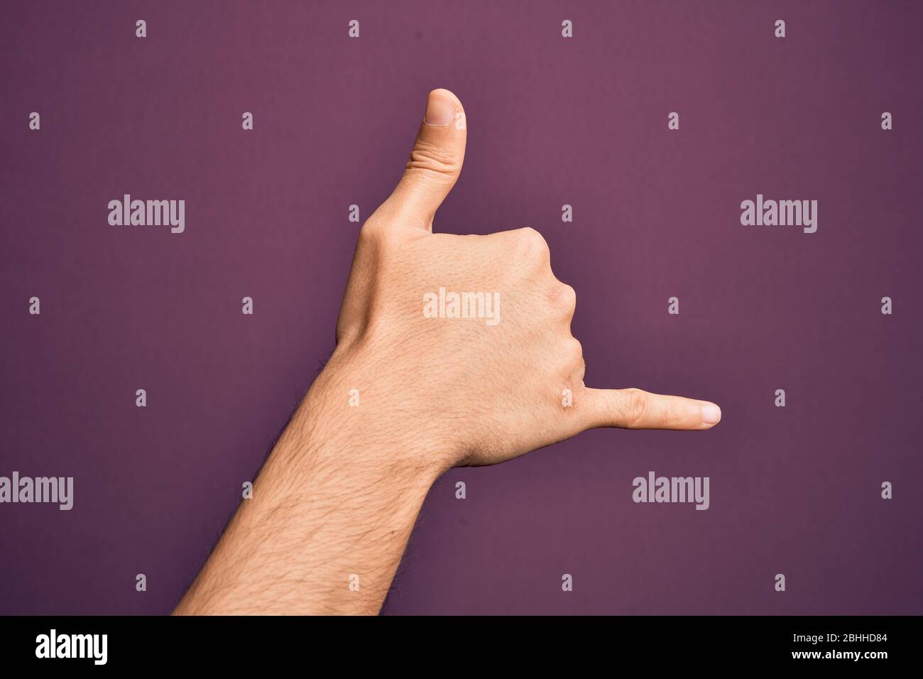 Hand of caucasian young man showing fingers over isolated purple background gesturing Hawaiian shaka greeting gesture, telephone and communication sym Stock Photo