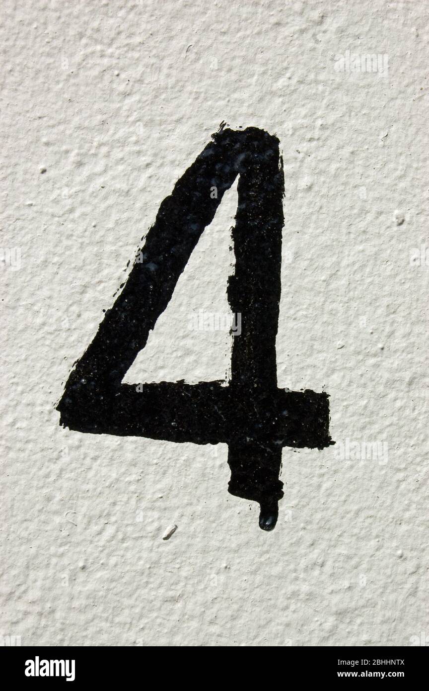 The number four painted rather roughly in black on a white wall. Stock Photo
