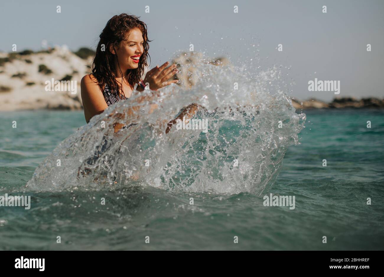 Pretty young woman walking in the warm sea water at summer Stock Photo