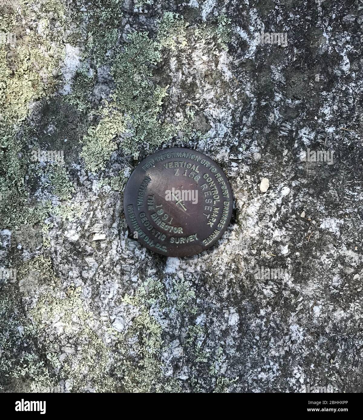 This National Geodetic Survey marker is on the ledge in Boothbay Harbor, Maine, at the Department of Marine Resources. The text on the marker reads (by line from top to bottom): FOR INFORMATION OR TO REPORT DAMAGE WRITE /VERTICAL CONTROL MARK/Z 156 RESET/1991/THE DIRECTOR/NATIONAL GEODETIC SURVEY/WASHINGTON, D.C. This photo dates to July 1, 2018. Stock Photo